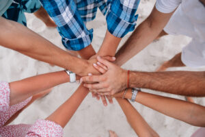 People joining hands together,group of friends keeping hands together.Teamwork concept. On the sandy beach.